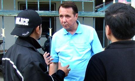 Mikhail Pletnev is questioned by a Thai police officer in front of the muscian's Pattaya residence