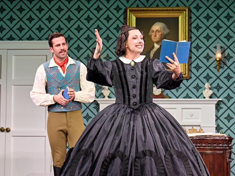 Mary's teacher looks on as Mary reads dramatically from a book