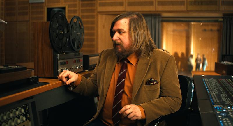 Michael Chernus as the journalist, sitting alone in a recording studio